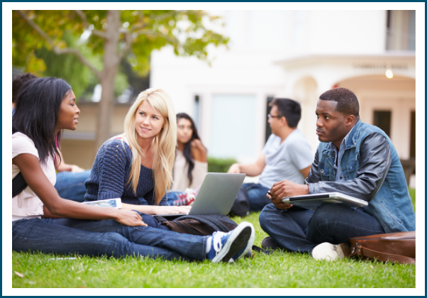 Image shows three college students sitting on a campus quad talking to each other.